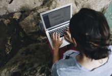 White man using computer laptop at waterfall