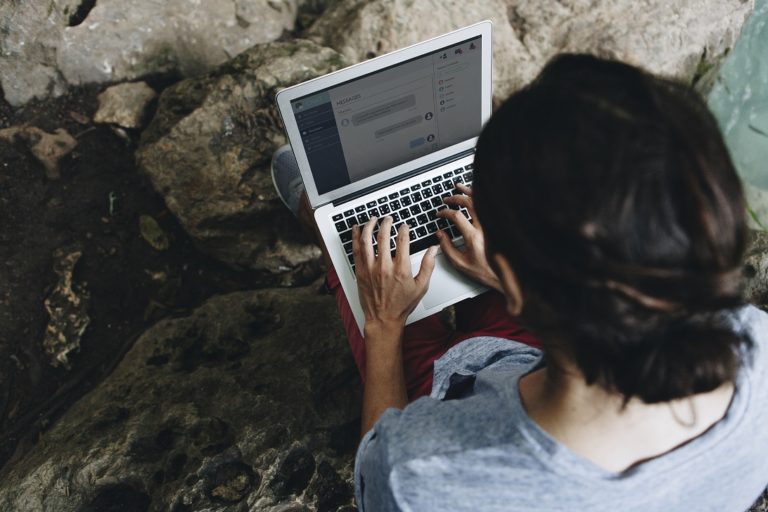 White man using computer laptop at waterfall